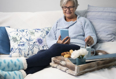 Young man using mobile phone while sitting on bed