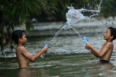 Full length of shirtless boy splashing water