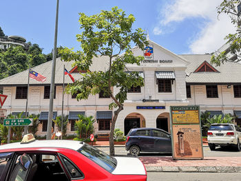 Cars on street by buildings against sky