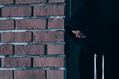 Side view of man standing against brick wall