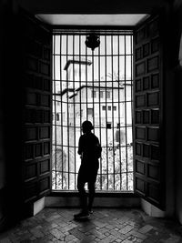 Rear view of silhouette man standing by window in building