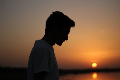 Silhouette man standing at beach during sunset