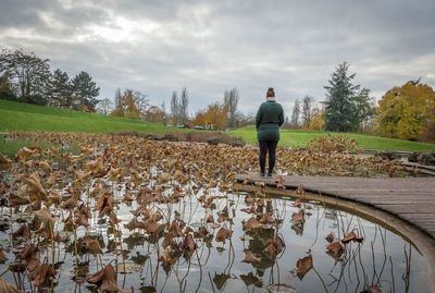 Rear view of man standing by lake against sky