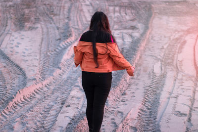 Rear view of woman walking on snow covered land