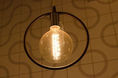 Close-up of illuminated light bulb against wall