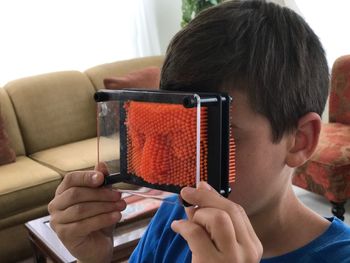 Boy holding face massager in living room at home