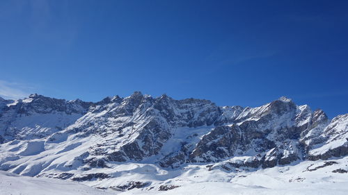 Scenic view of snowcapped mountains against clear blue sky