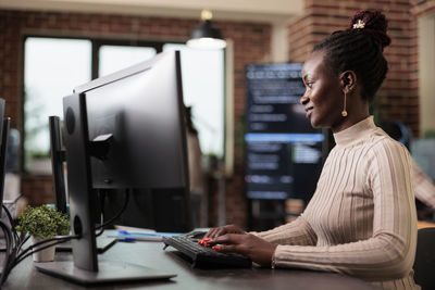 Side view of young woman using laptop at office