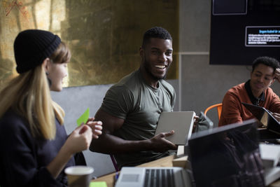 Happy businessman with coworkers discussing during meeting at creative office