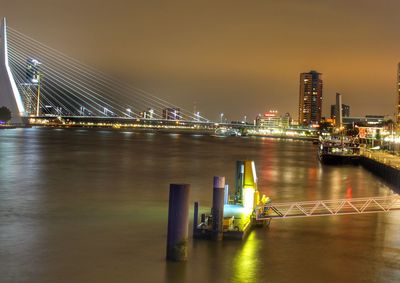 Erasmus bridge over nieuwe maas river against sky in city at night