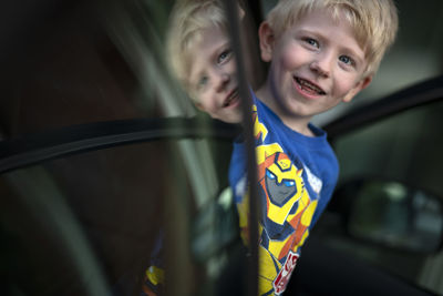 Portrait of smiling boy by car