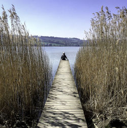 Pier over lake against clear sky