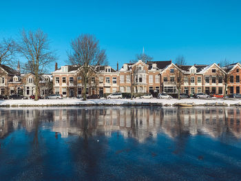 Reflection of buildings and trees against blue sky