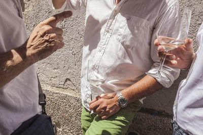 Midsection of friends drinking white wine during wedding