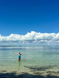 Woman standing on sea against blue sky