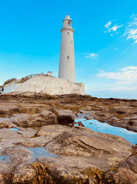 Lighthouse by sea against sky