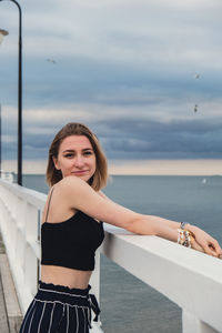 Young woman standing on wooden pier blurred beachside background. attractive female enjoying the sea