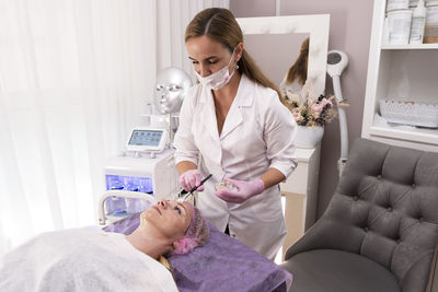 A beautician applies cooling gel and prepares skin for cosmetology procedure.