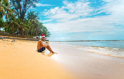 Portrait of man with coconut sitting on beach