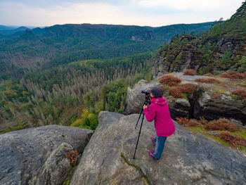 Woman photographer is taking pictures with camera in morning hills. nature landscape photographer 