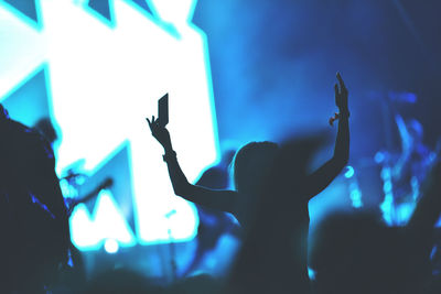 Silhouette people at music concert against sky at night