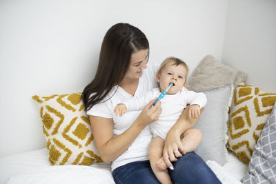 Mother and daughter sitting on bed at home