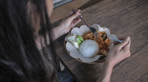 High angle view of woman holding food on table