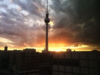 Low angle view of communications tower against cloudy sky