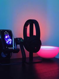 Close-up of camera on table against illuminated wall