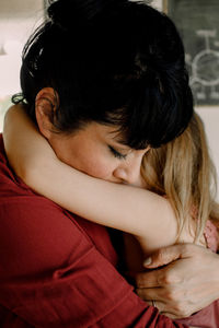 Mother embracing while consoling daughter at home