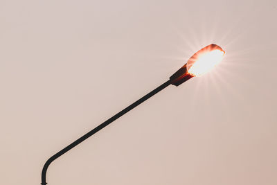 Low angle view of illuminated lighting equipment against sky during sunset