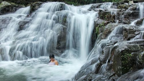 Woman relaxing in waterfall at forest