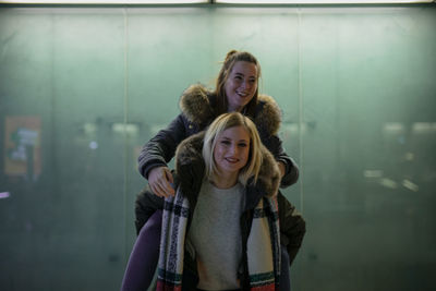 Portrait of young woman giving piggyback to friend 