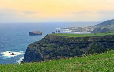 Scenic view of sea by cliff against sky