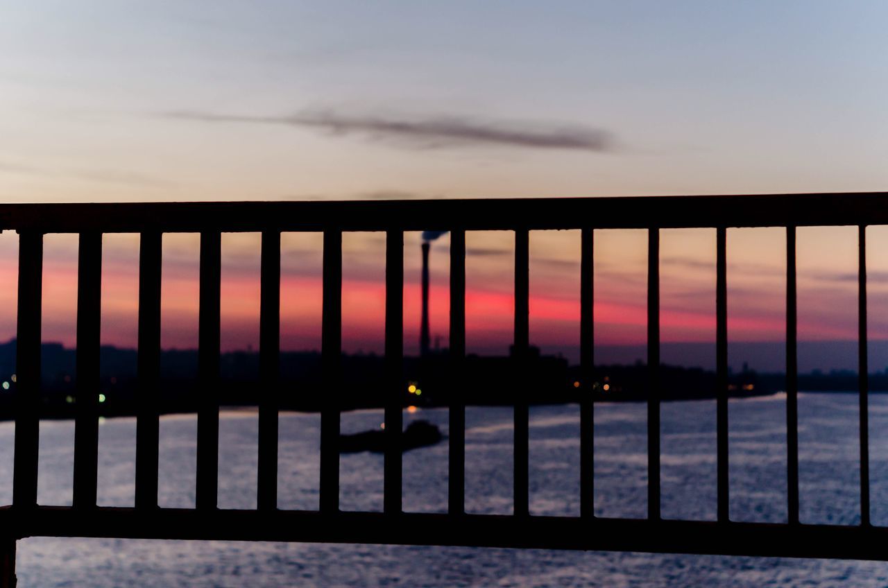 SILHOUETTE RAILING AGAINST SEA AT SUNSET