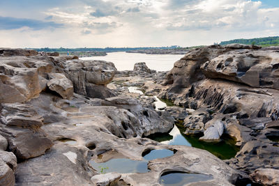 Rock formations on shore against sky