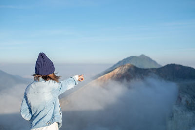 Rear view of woman standing on mountain against sky