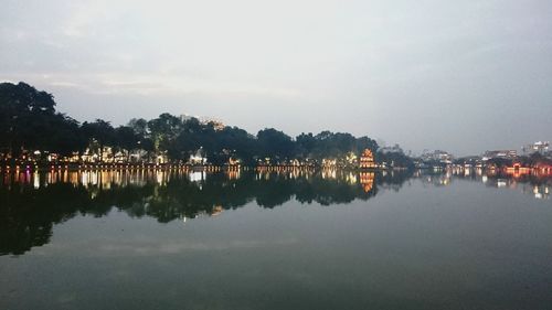 Reflection of silhouette trees in water against sky