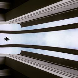 Low angle view of fighter plane amidst buildings in city