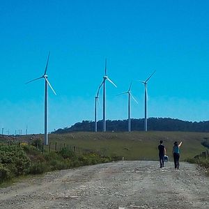 Rear view of people on landscape against clear sky