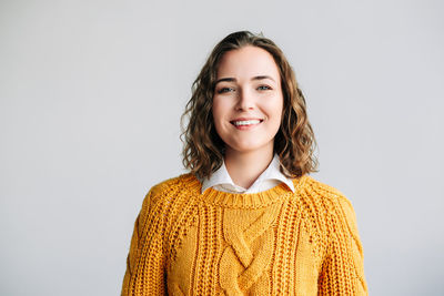 Portrait of young woman standing against white background