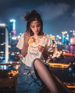 Young woman with arms raised in city at night