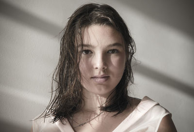 Portrait of teenage girl against wall at home