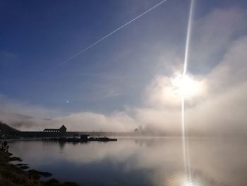 Scenic view of sea against vapor trails in sky