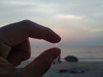 Midsection of person against sea during sunset