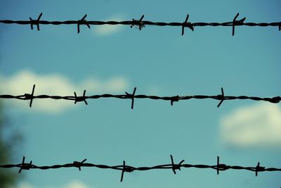 Low angle view of barbed wire against sky