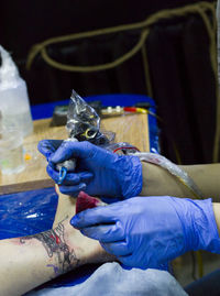 Cropped hands of tattoo artist tattooing on customer leg