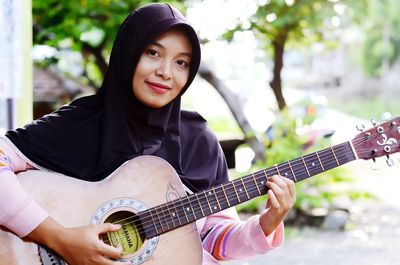 Portrait of young woman playing guitar