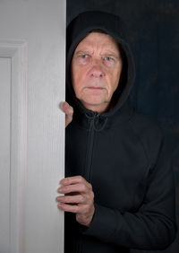 Portrait of man wearing hood while standing at door