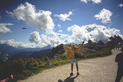 Rear view of man walking on mountain against sky